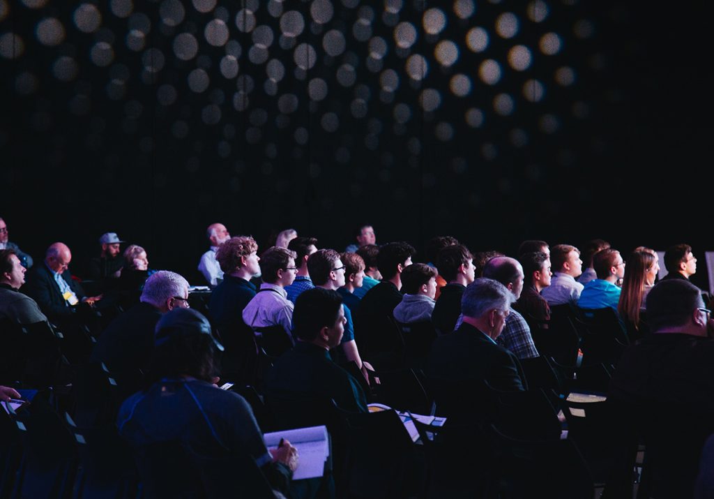 Image of spectators in a dark conference room