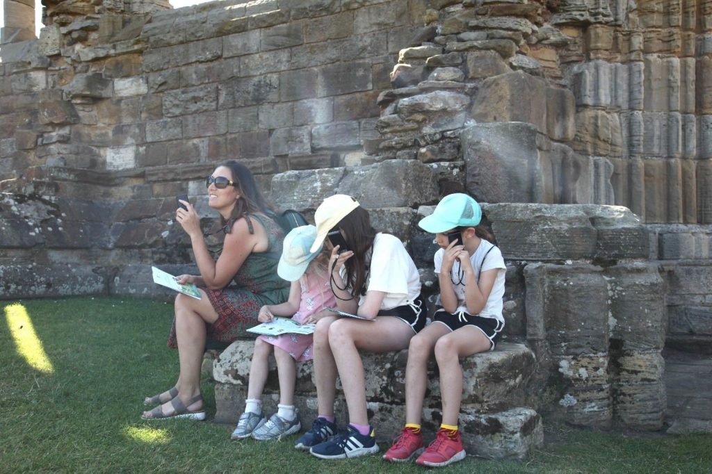 Photo of Kate Huggins and 3 kids sitting on runes in the North of England.