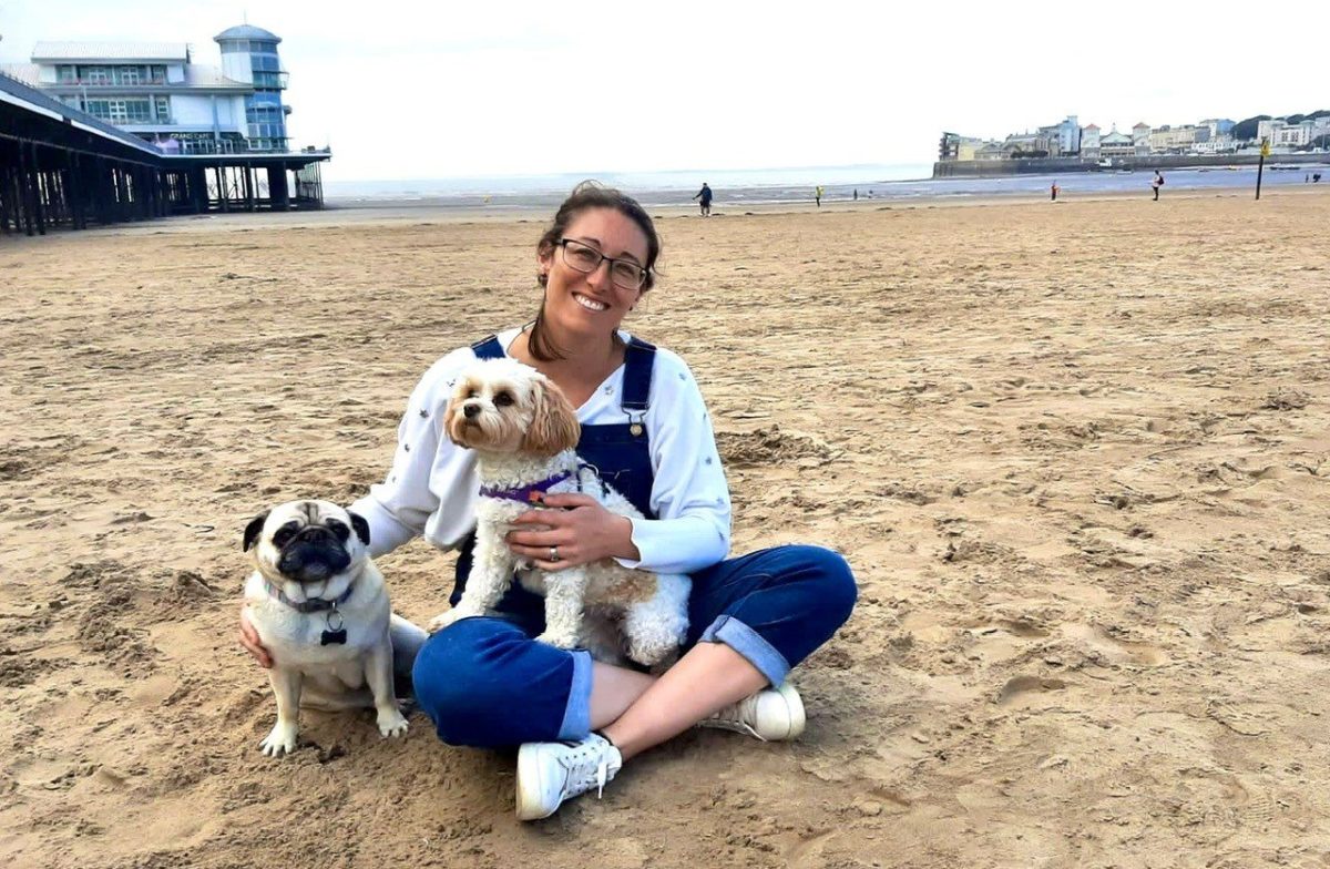 Image of Kate Huggins on a beach in UK with 2 dogs