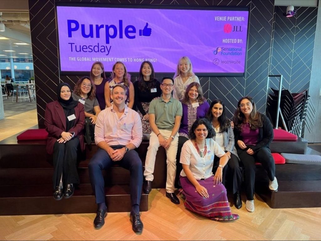 Leathwaite staff in Hong Kong sat in front of a purple tuesday banner