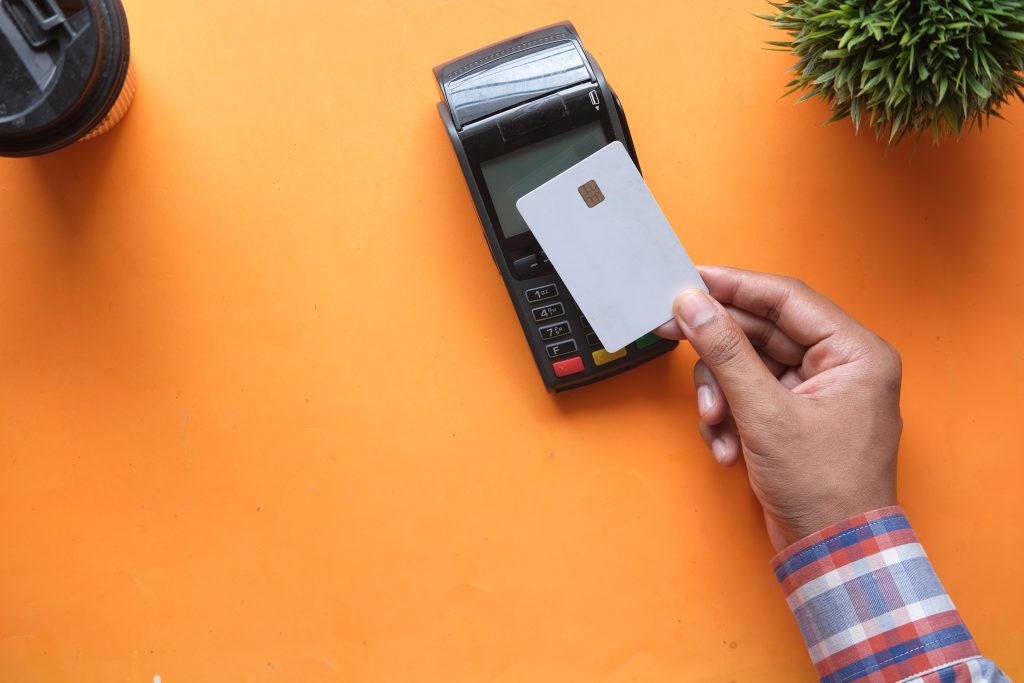 Orange table with man making a contactless payment with a bank card