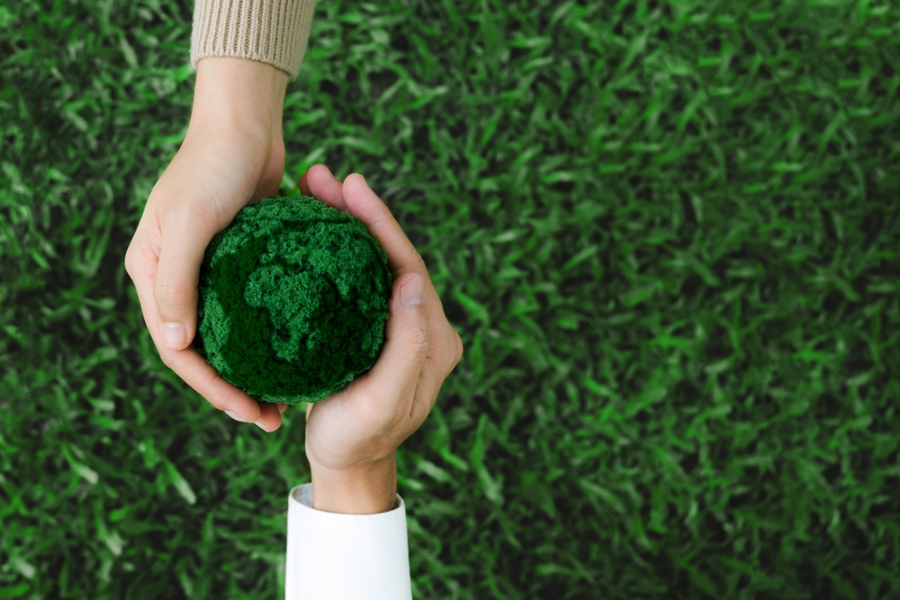 Two hands holding green earth together on nature background for the Sustainable Development Goals