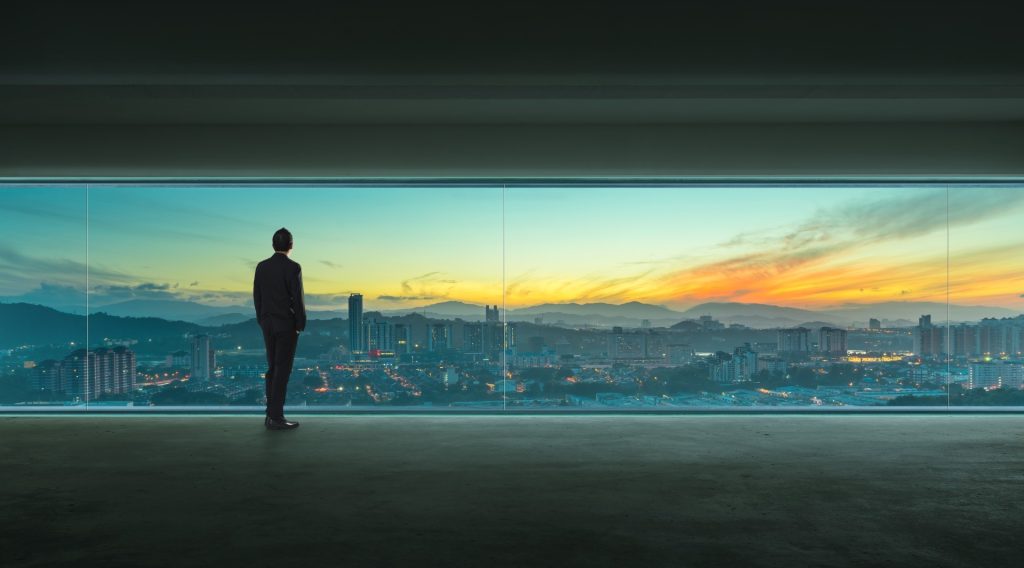 Man standing in front of window showing sunset